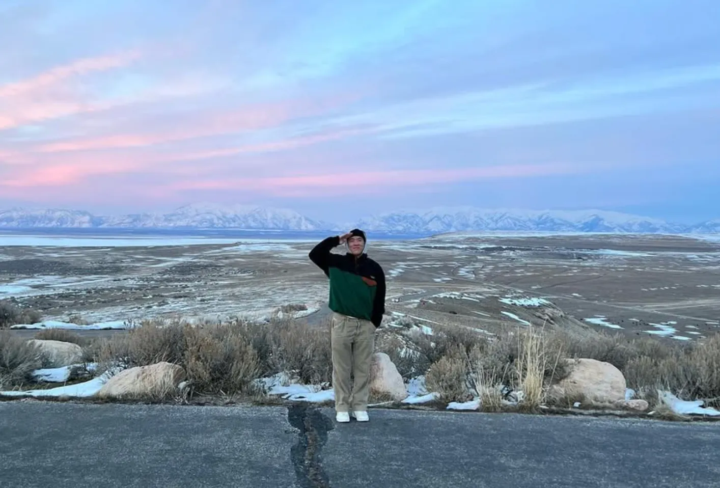 Benji saluting in front of snowy mountains on a road trip with his dad